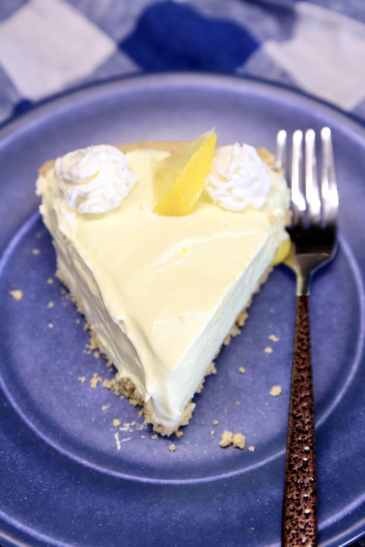 Slice of lemon pie on a blue plate.