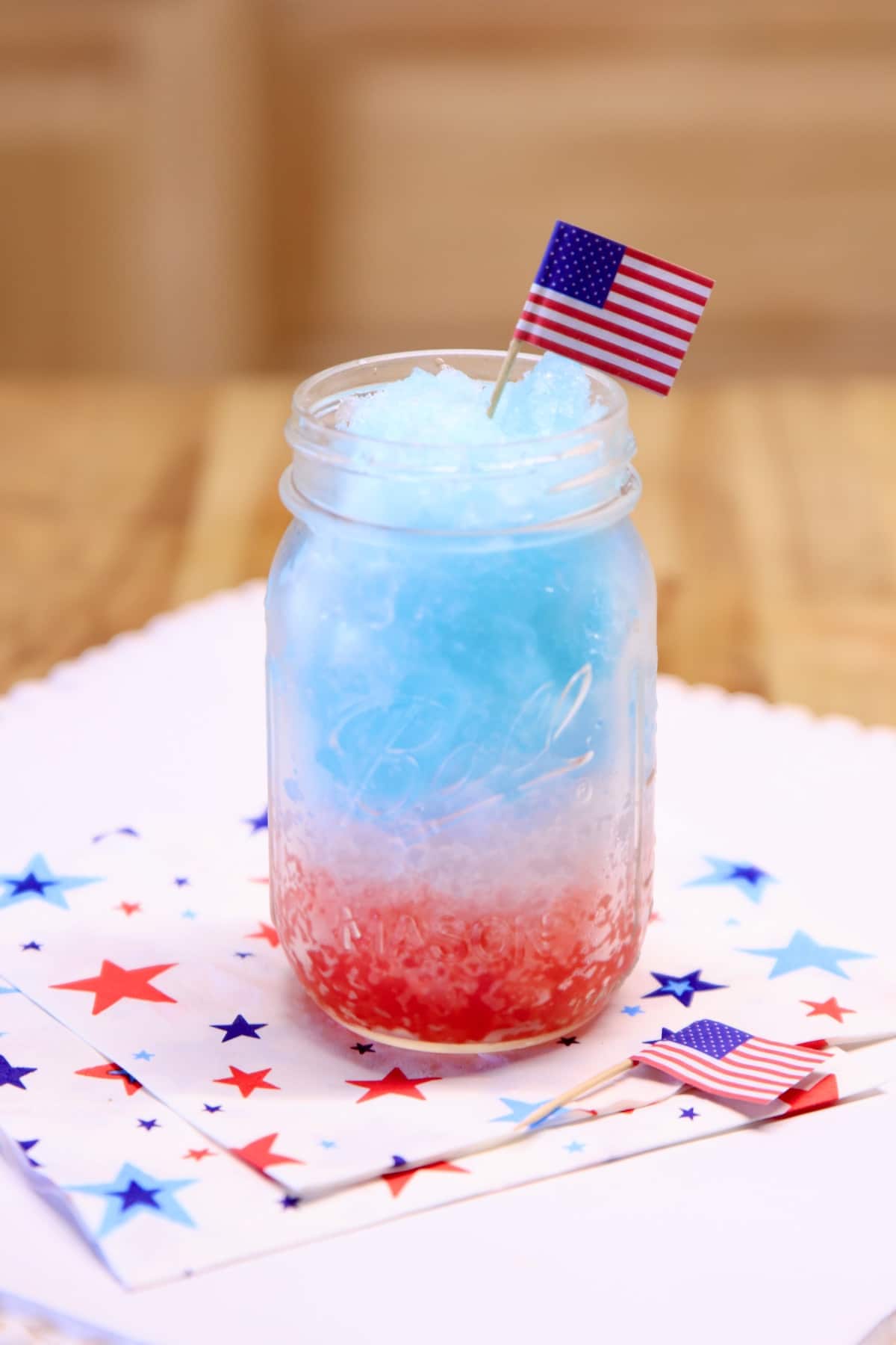 Frozen punch layered red, white and blue in a mason jar.