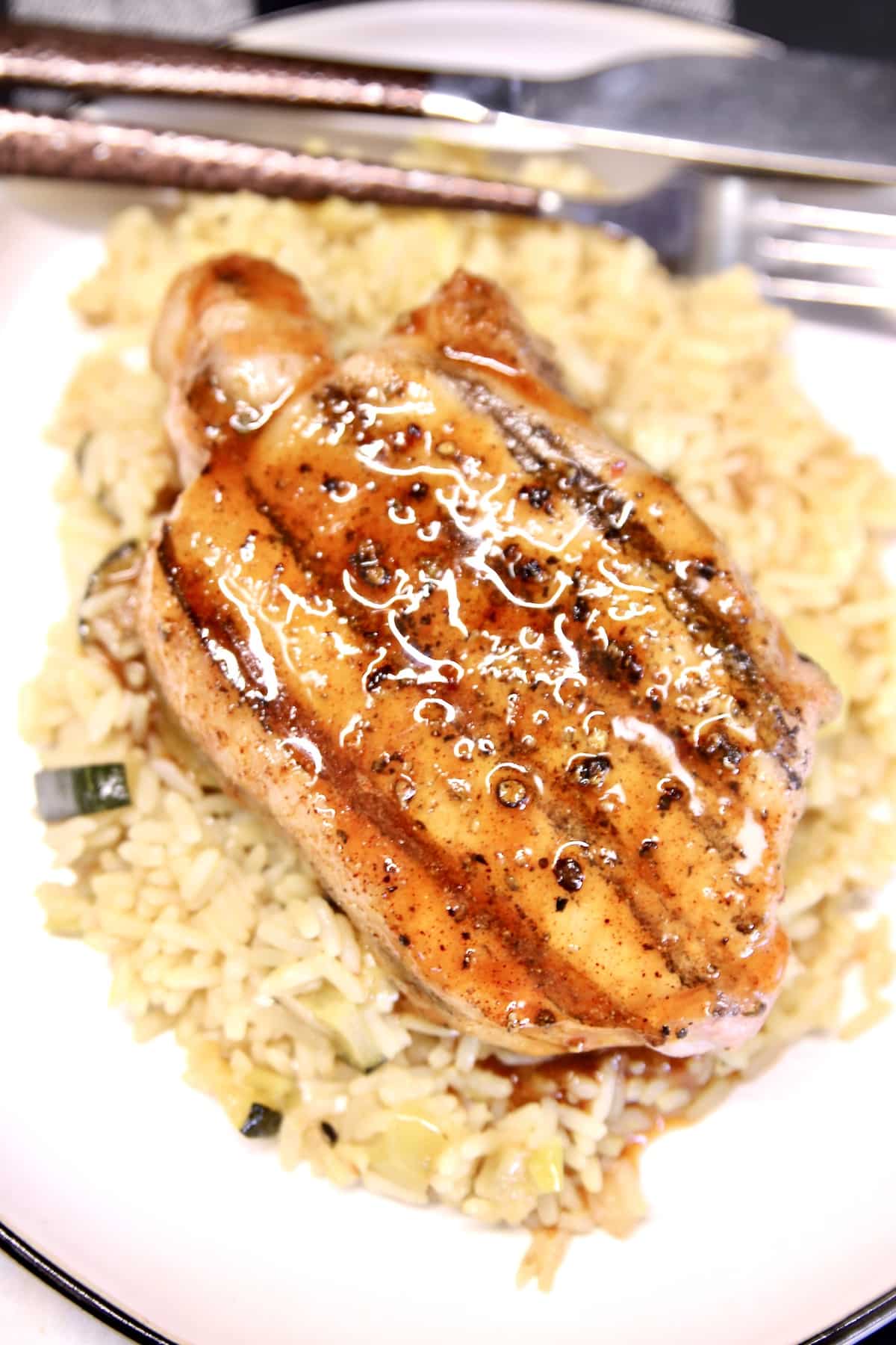 Closeup of plated grilled pork chop with rice.