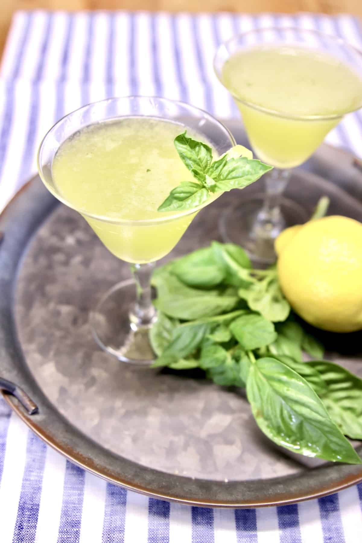 2 gin cocktails on a platter with fresh basil.