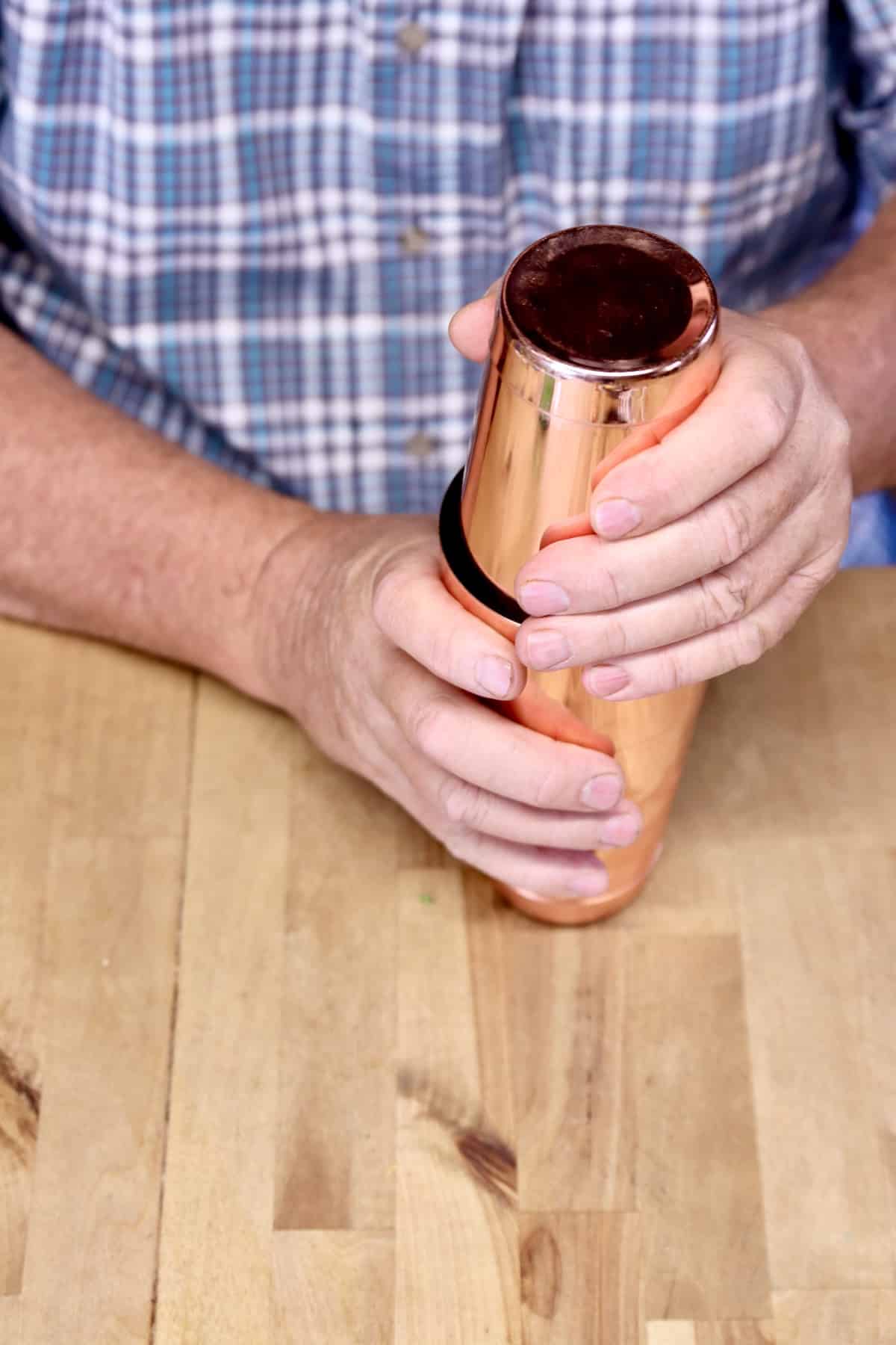 Man holding copper cocktail shaker.