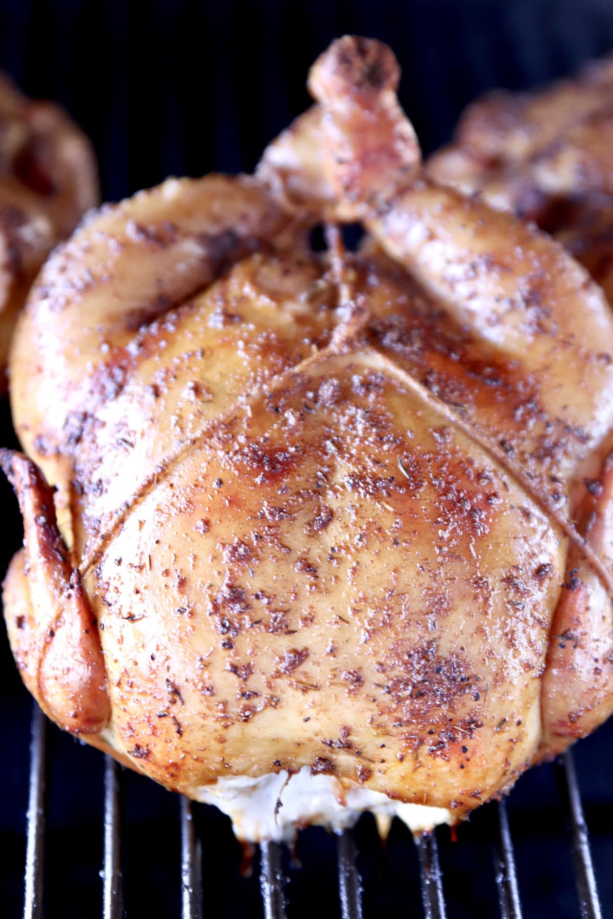 Closeup of whole chicken on a grill.