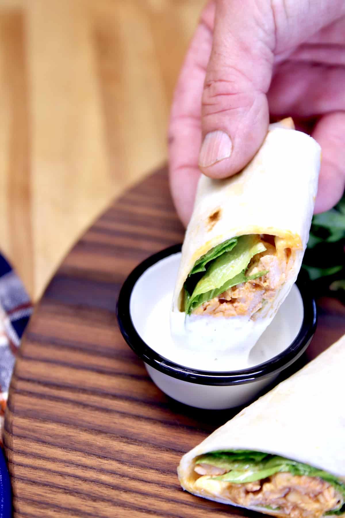 Dipping chicken wrap in ranch dressing.
