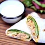 Chicken wrap cut in half with bowl of ranch.