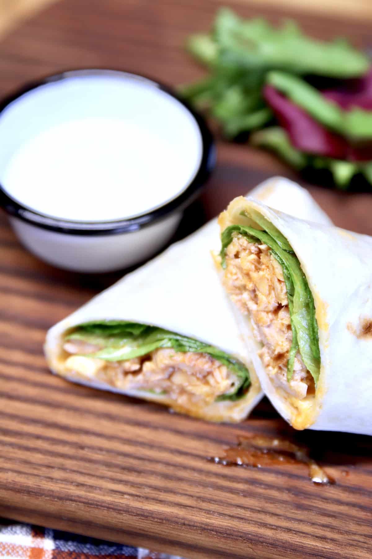 Chicken wrap, cut in half with bowl of ranch.