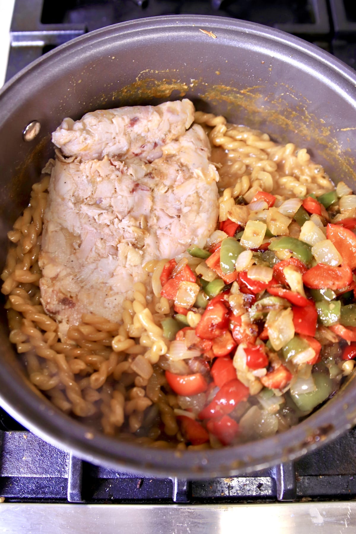 Pan with cooked pasta, chopped chicken, sauteed vegetables.