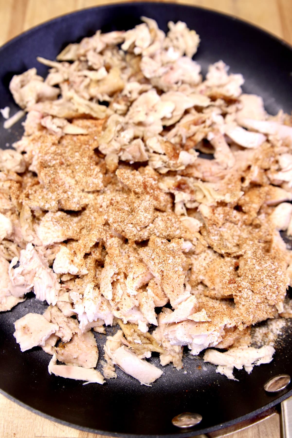 Skillet with shredded chicken and spices.