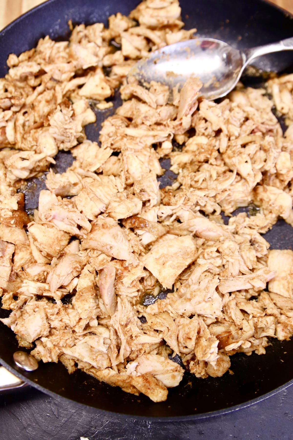 Seasoned shredded chicken in a skillet.