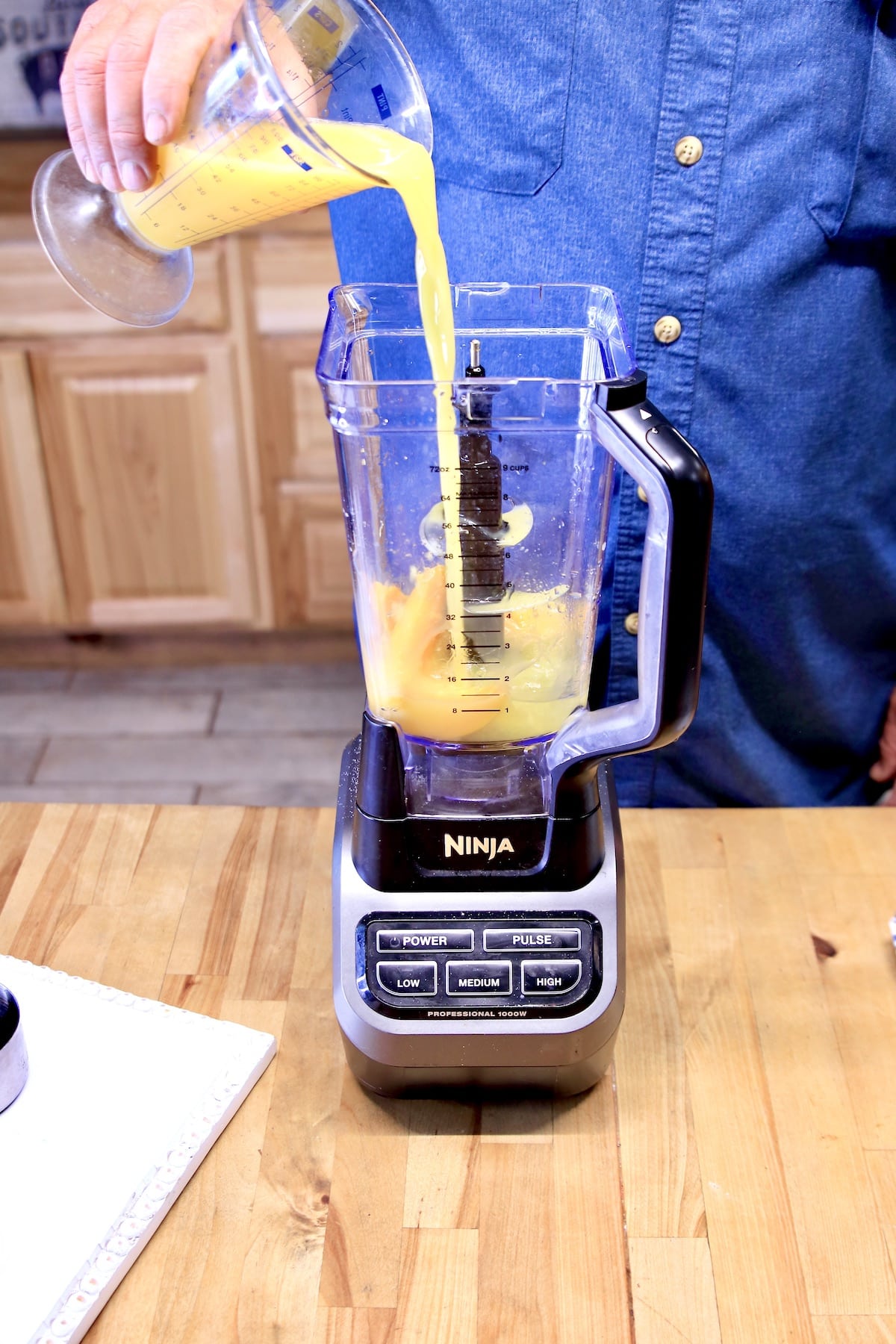 Pouring orange juice into a blender. 