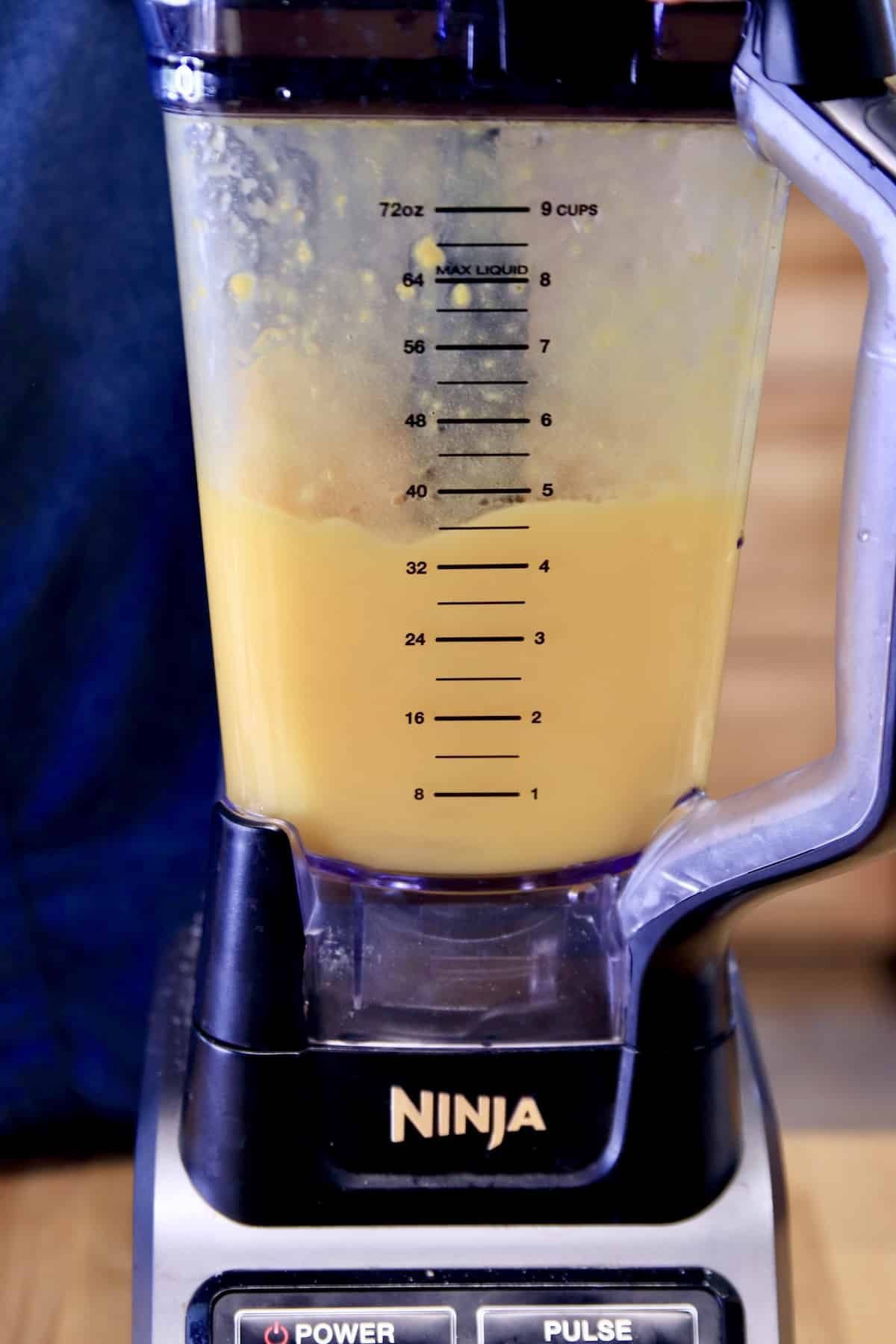 Closeup of blender with mango orange cocktail.