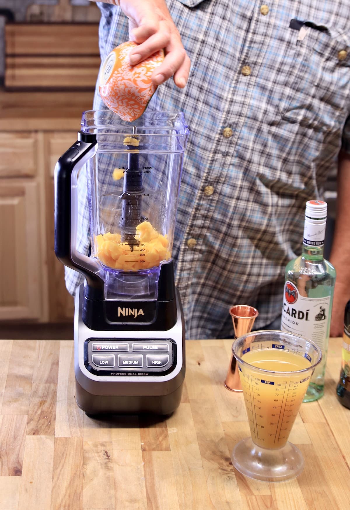 Pouring mango into a blender.