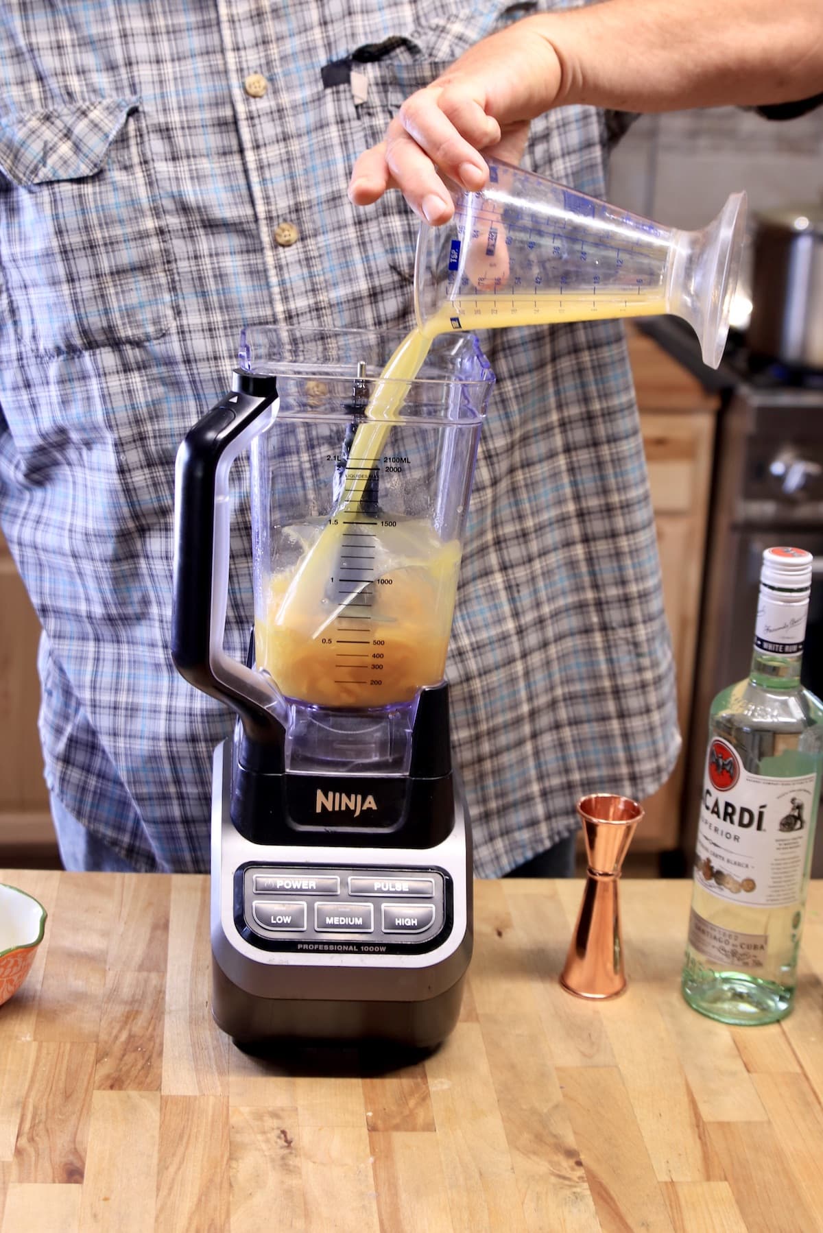 Pouring pineapple juice in a blender.