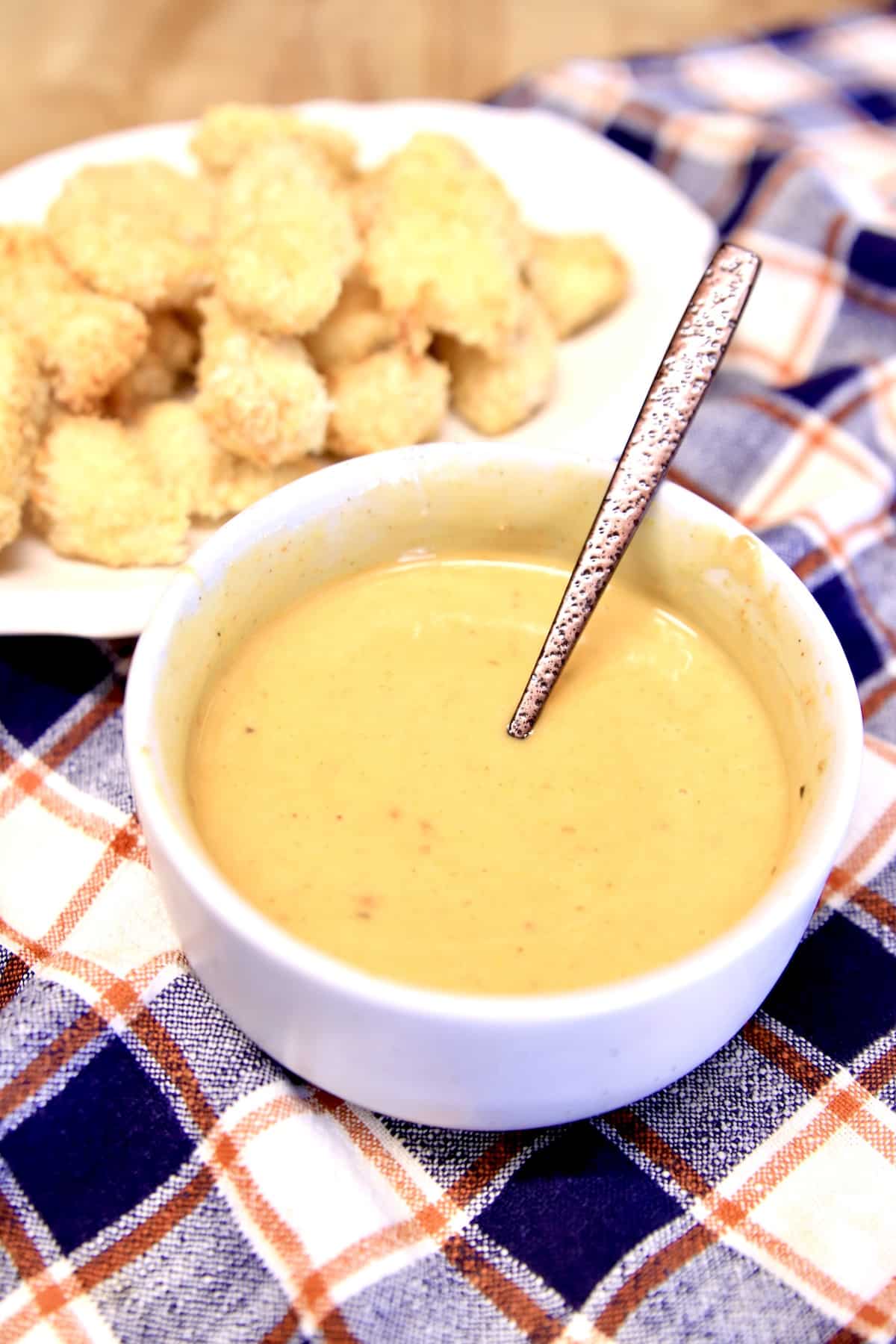 Platter of chicken nuggets, bowl of dipping sauce with spoon.