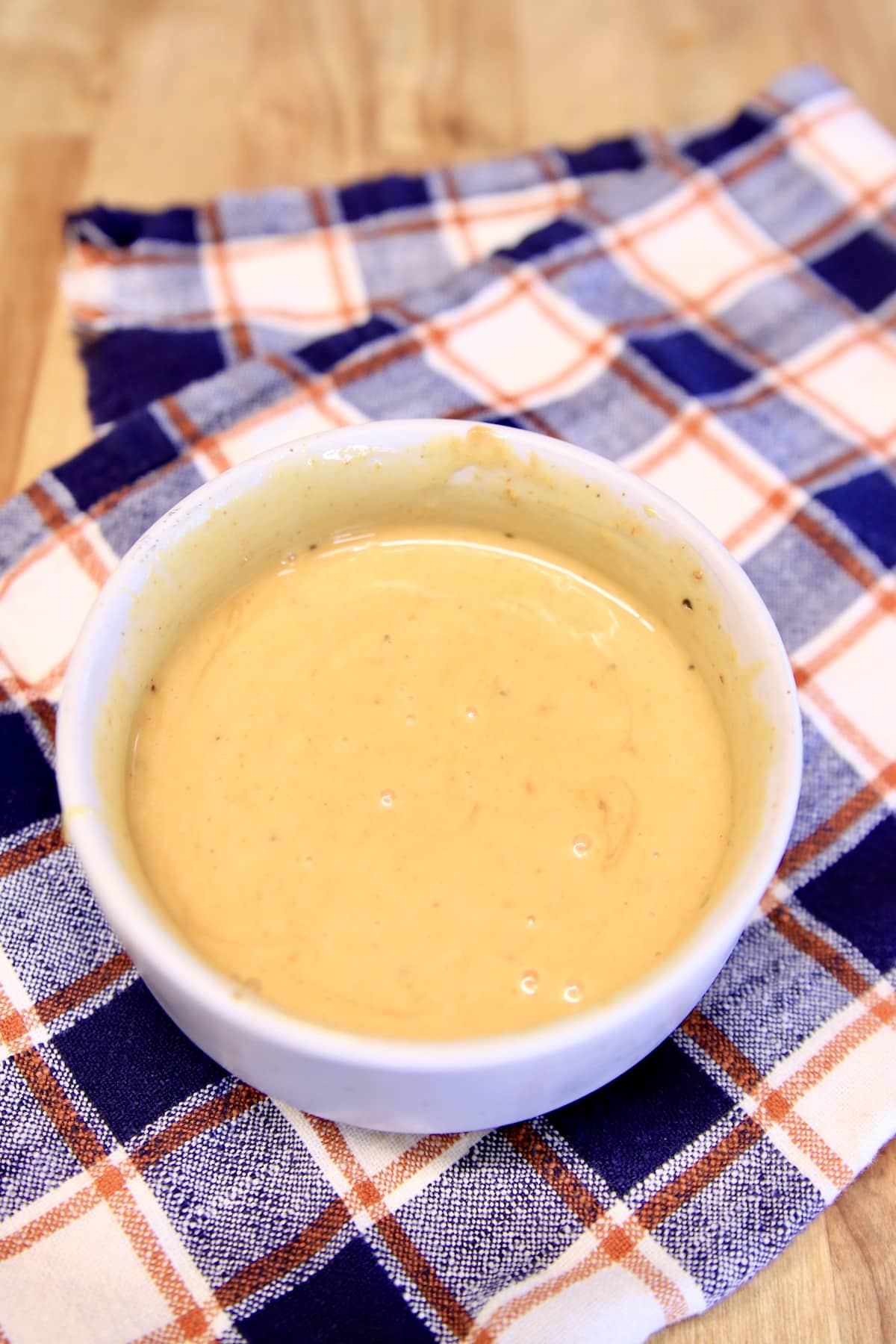 Bowl of dipping sauce on a plaid napkin.