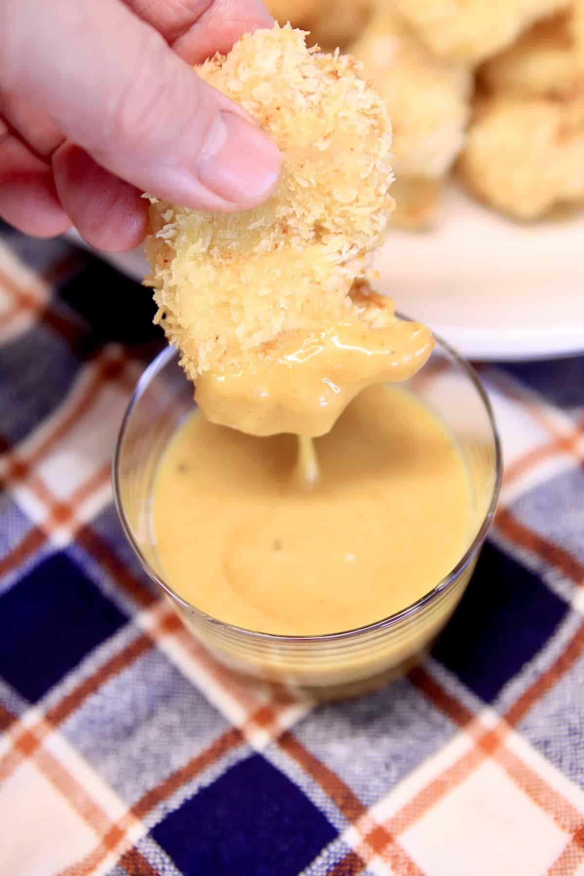 Chicken nugget dipping intoChick Fil A Sauce.
