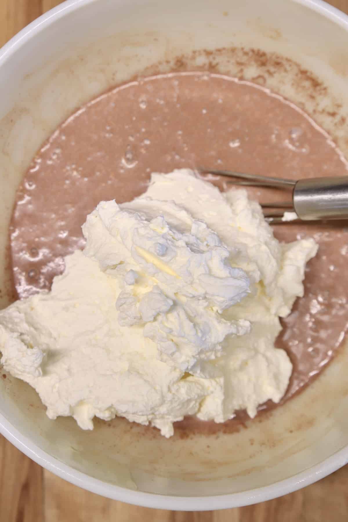 Whipped cream in bowl of cinnamon ice cream base.