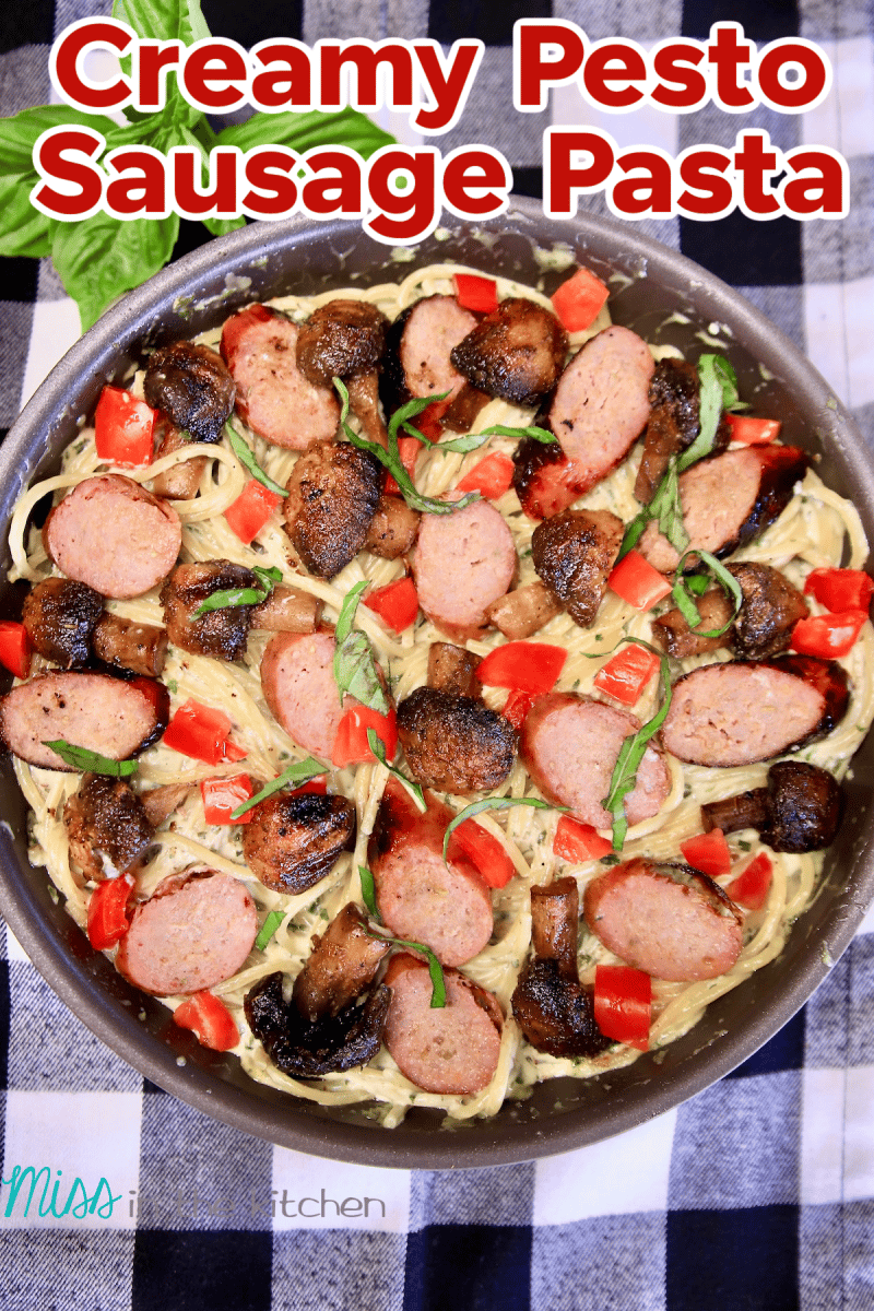 Pan with pesto spaghetti, grilled sausage and mushrooms. Text overlay.