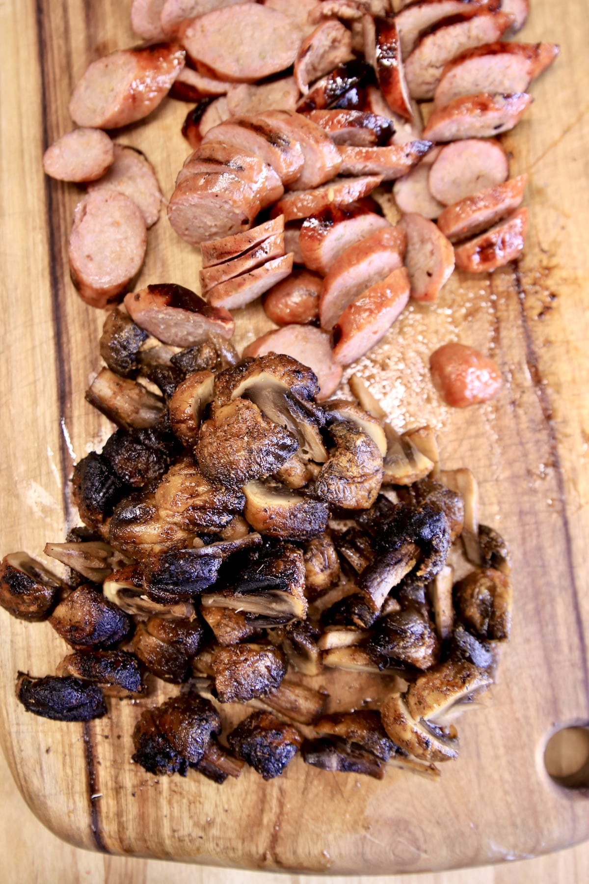 Sausage sliced, mushrooms on a cutting board.