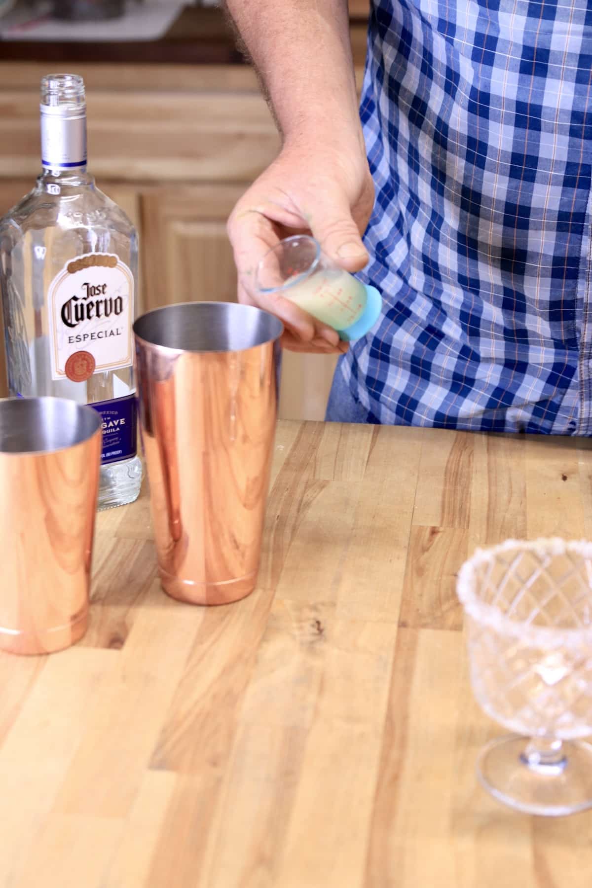 Pouring lemon juice into a cocktail shaker.
