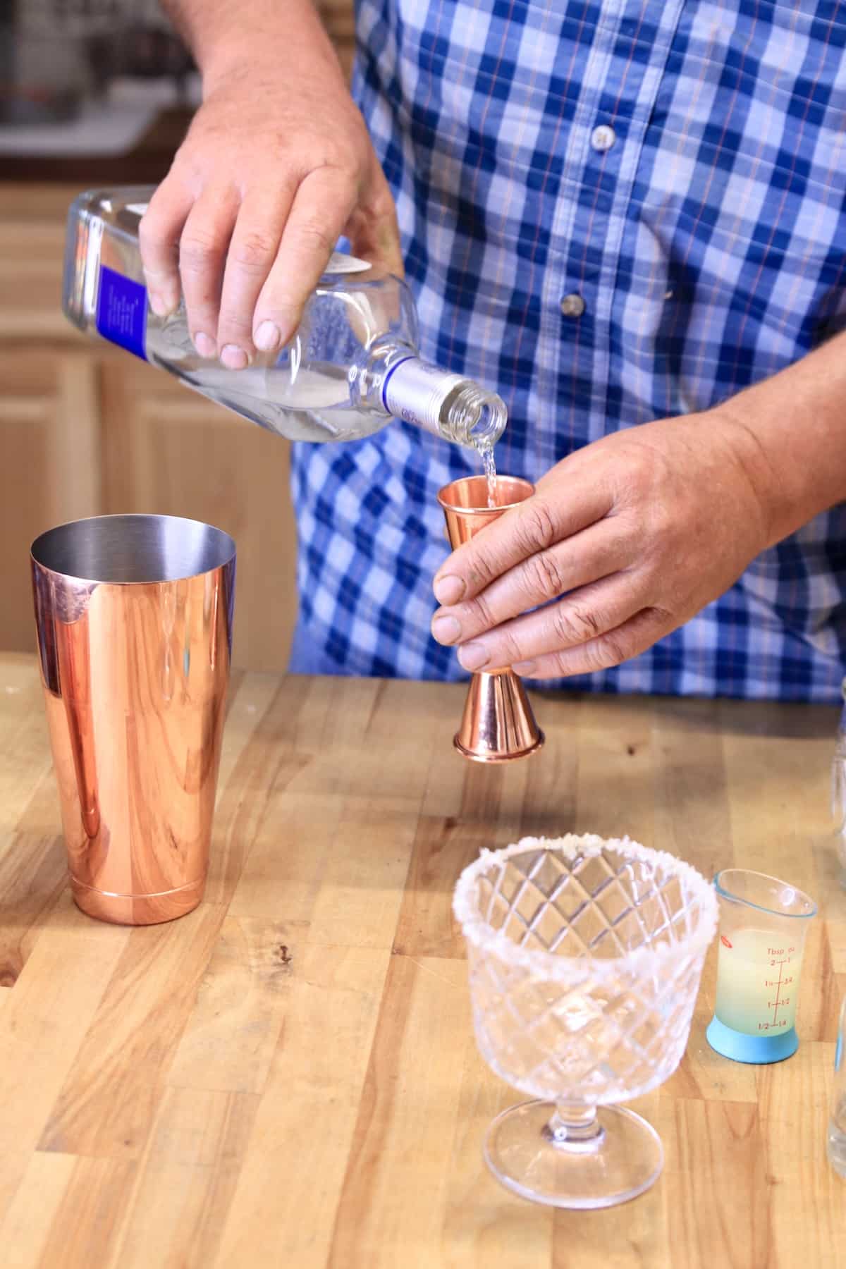Pouring tequila into a cocktail jigger.