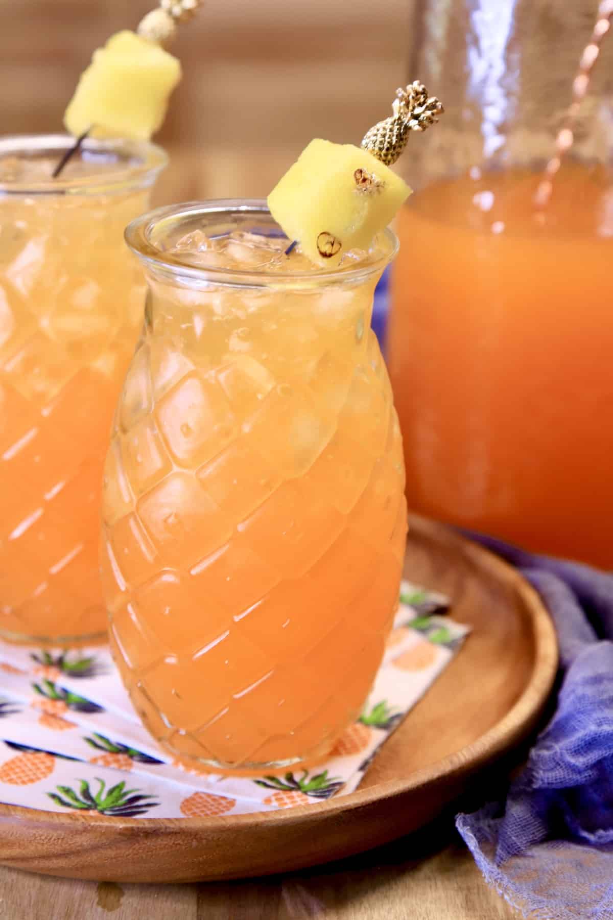 Orange punch in pineapple glasses, pitcher of punch.