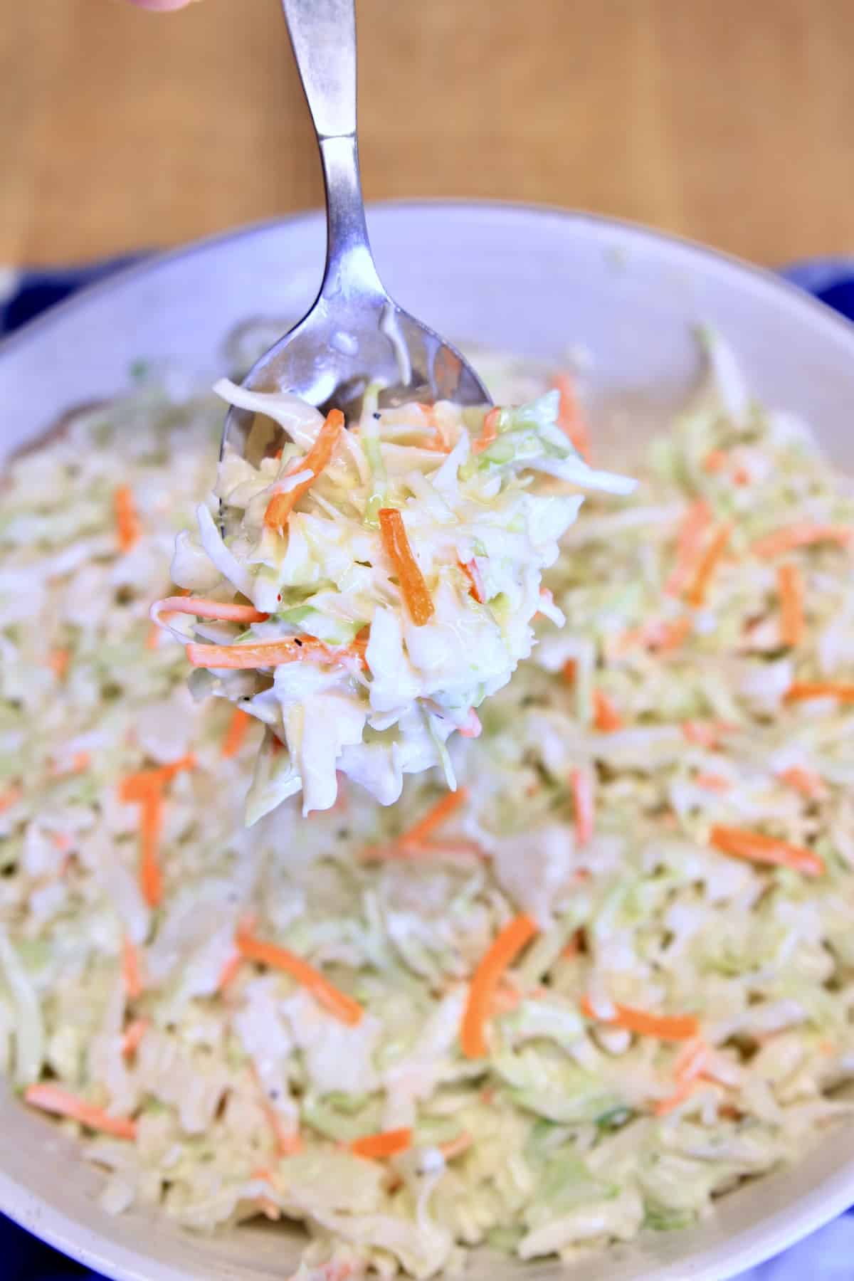 Spoonful of coleslaw over a bowl.