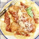 Chicken Parmesan on a plate with spaghetti.