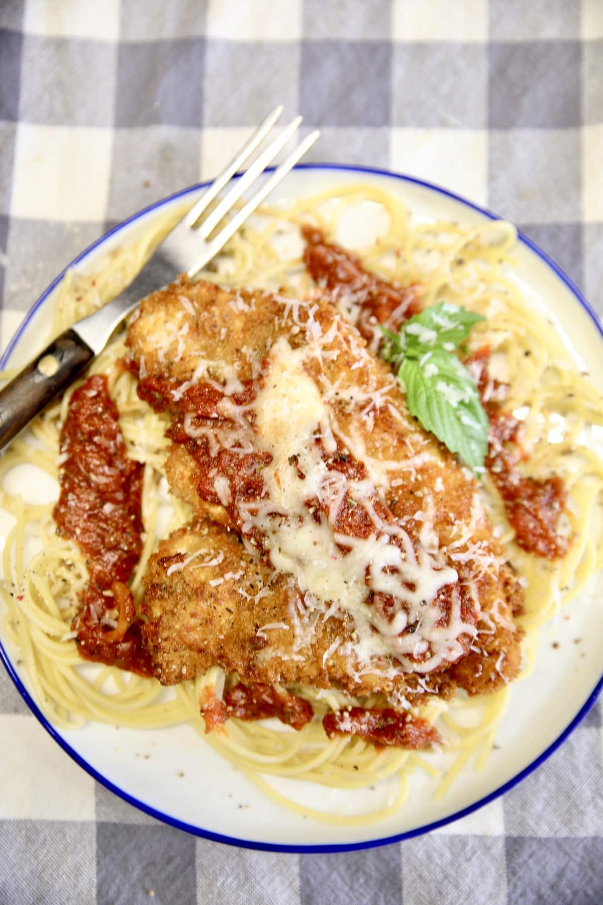 Chicken Parmesan on a plate with spaghetti.