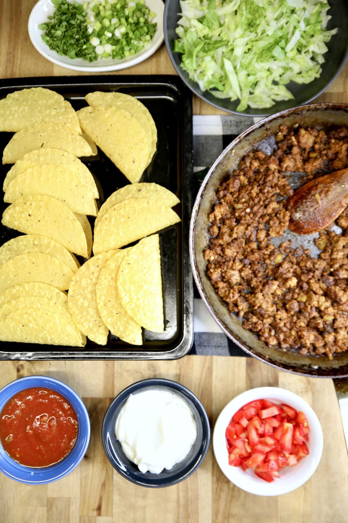 Overhead of ground beef tacos, shells, toppings.