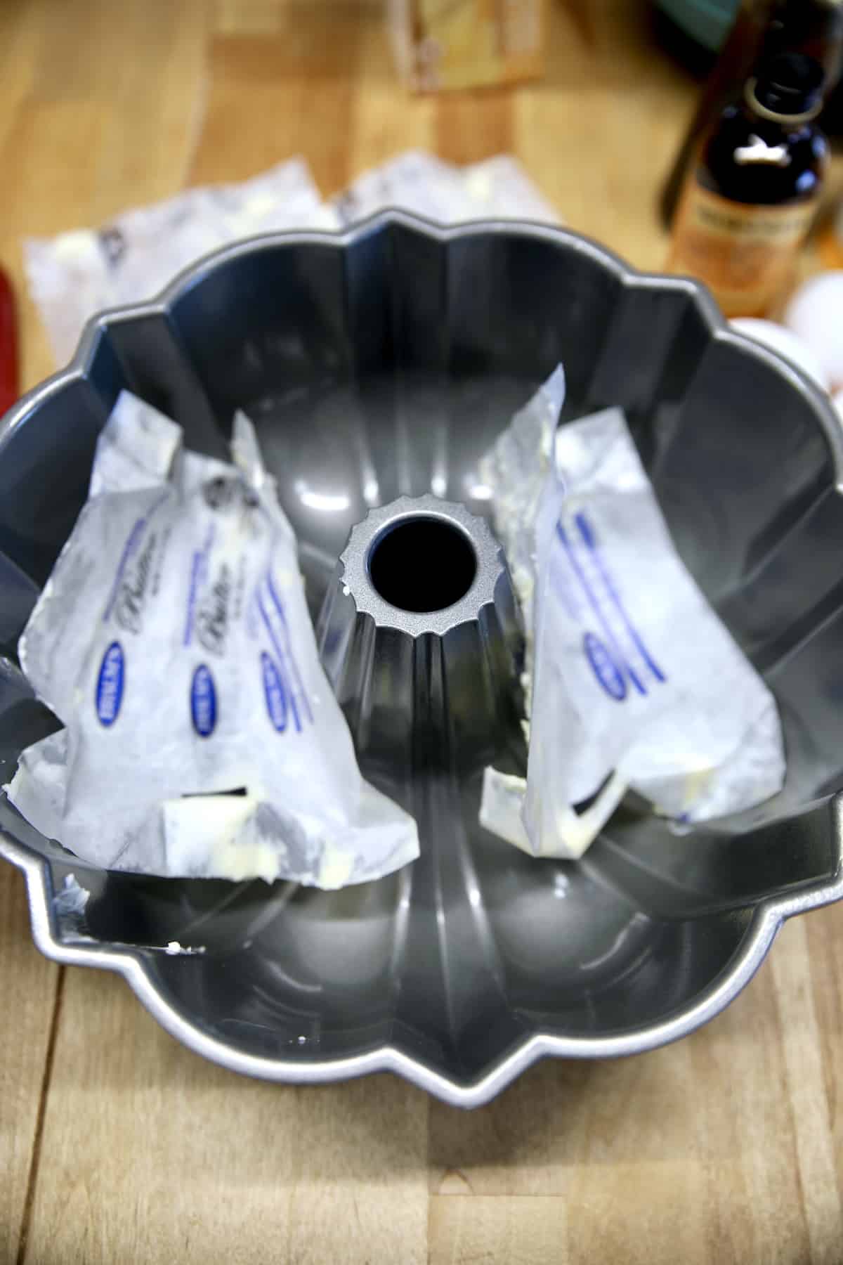 Buttering a bundt pan with butter wrappers.