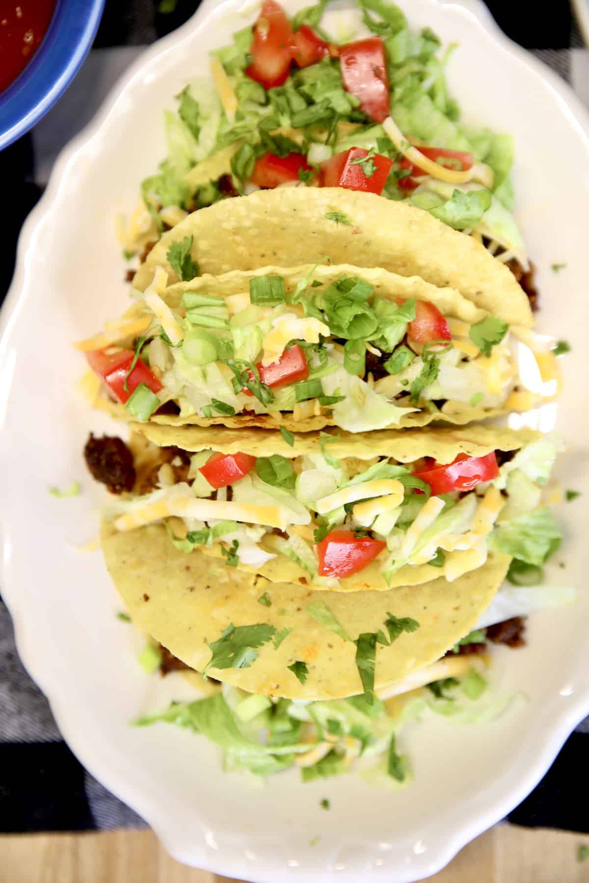 Platter of ground beef tacos with lettuce, tomatoes.