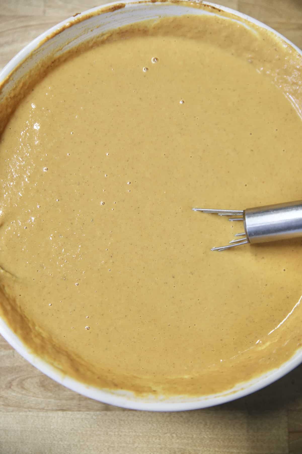 Bowl of pumpkin pie filling with a whisk.