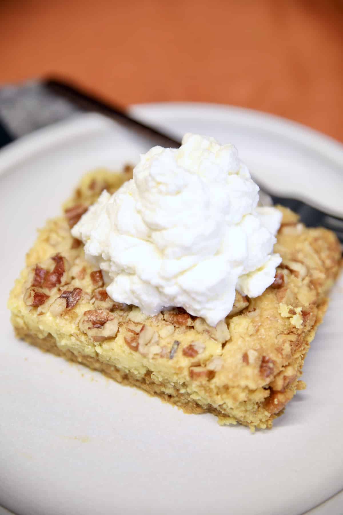 Slice of pumpkin dump cake with whipped cream on a plate with fork.