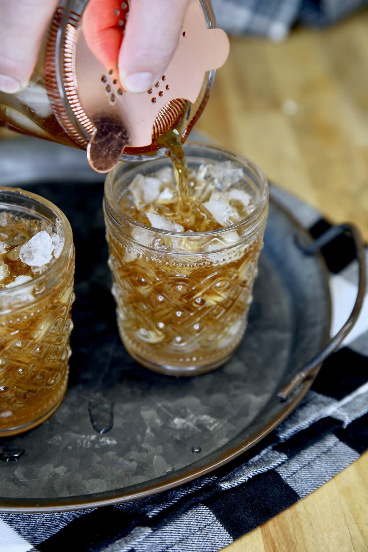 Straining cocktail in glasses with ice.