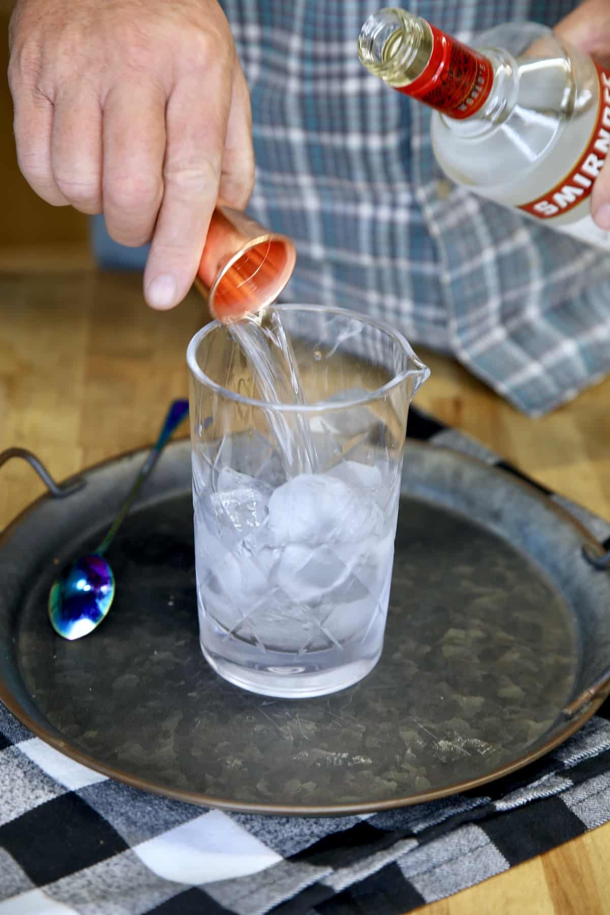 Pouring vodka into a cocktail mixer glass.