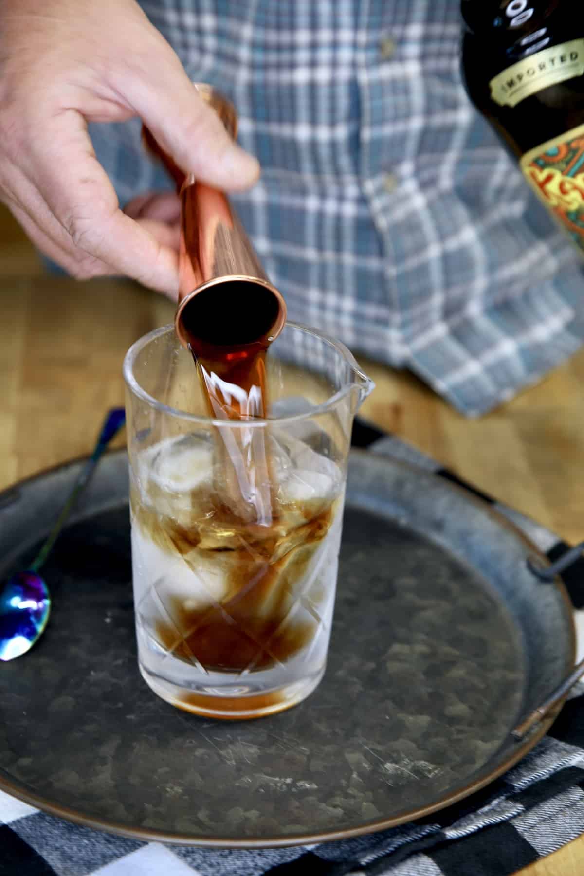 Pouring Kahlua into a cocktail mixer.
