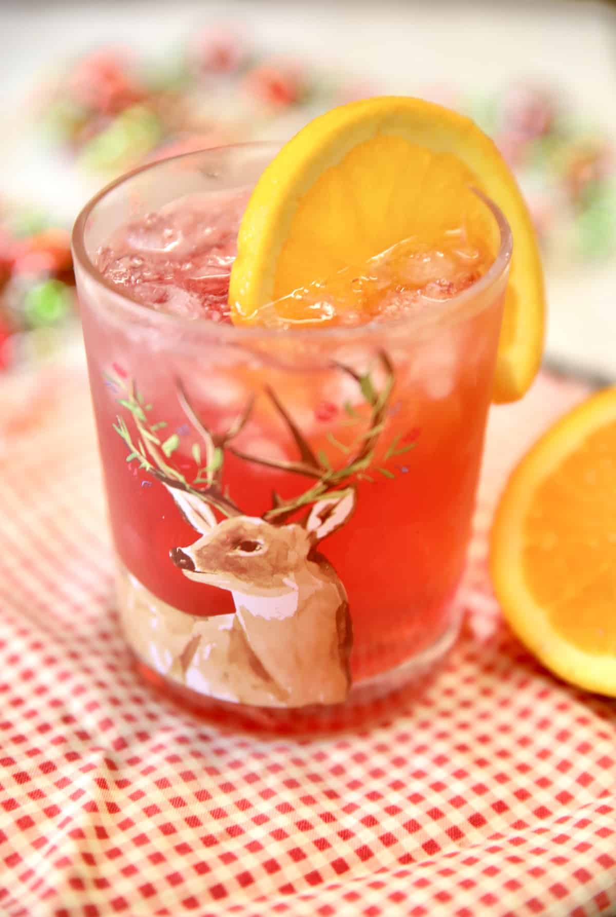 Cranberry cocktail in a glass with orange wheel.