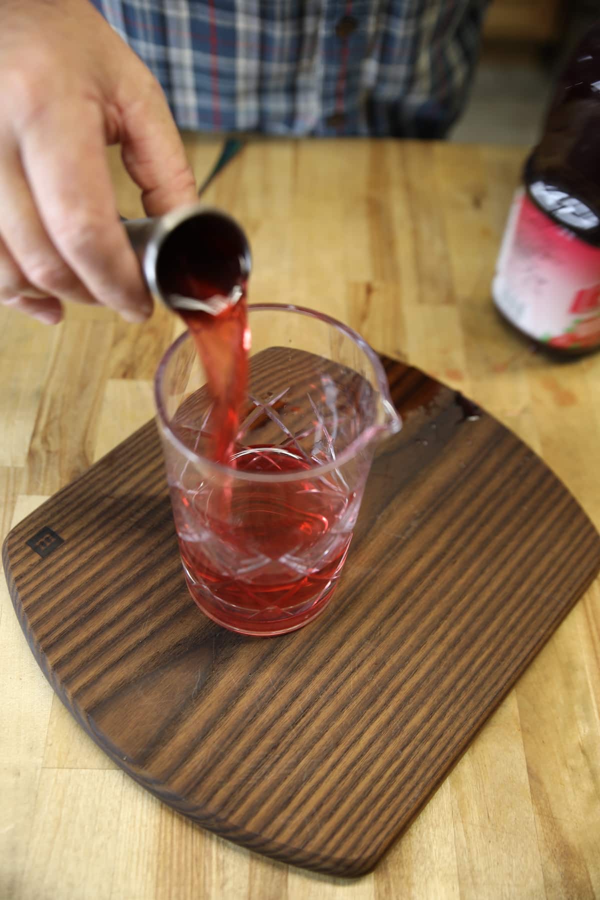 Pouring cranberry juice into cocktail mixer glass.