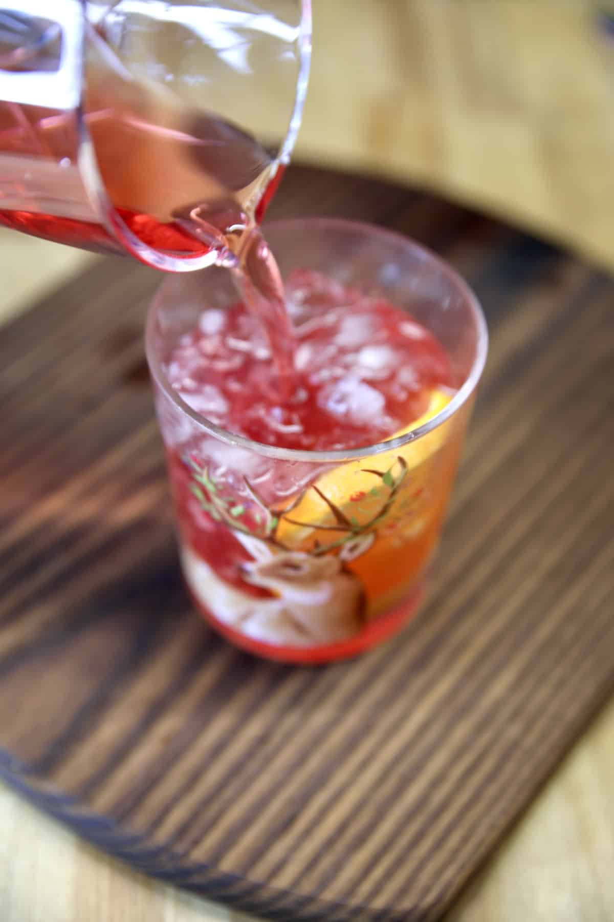 Pouring cranberry cocktail over ice.