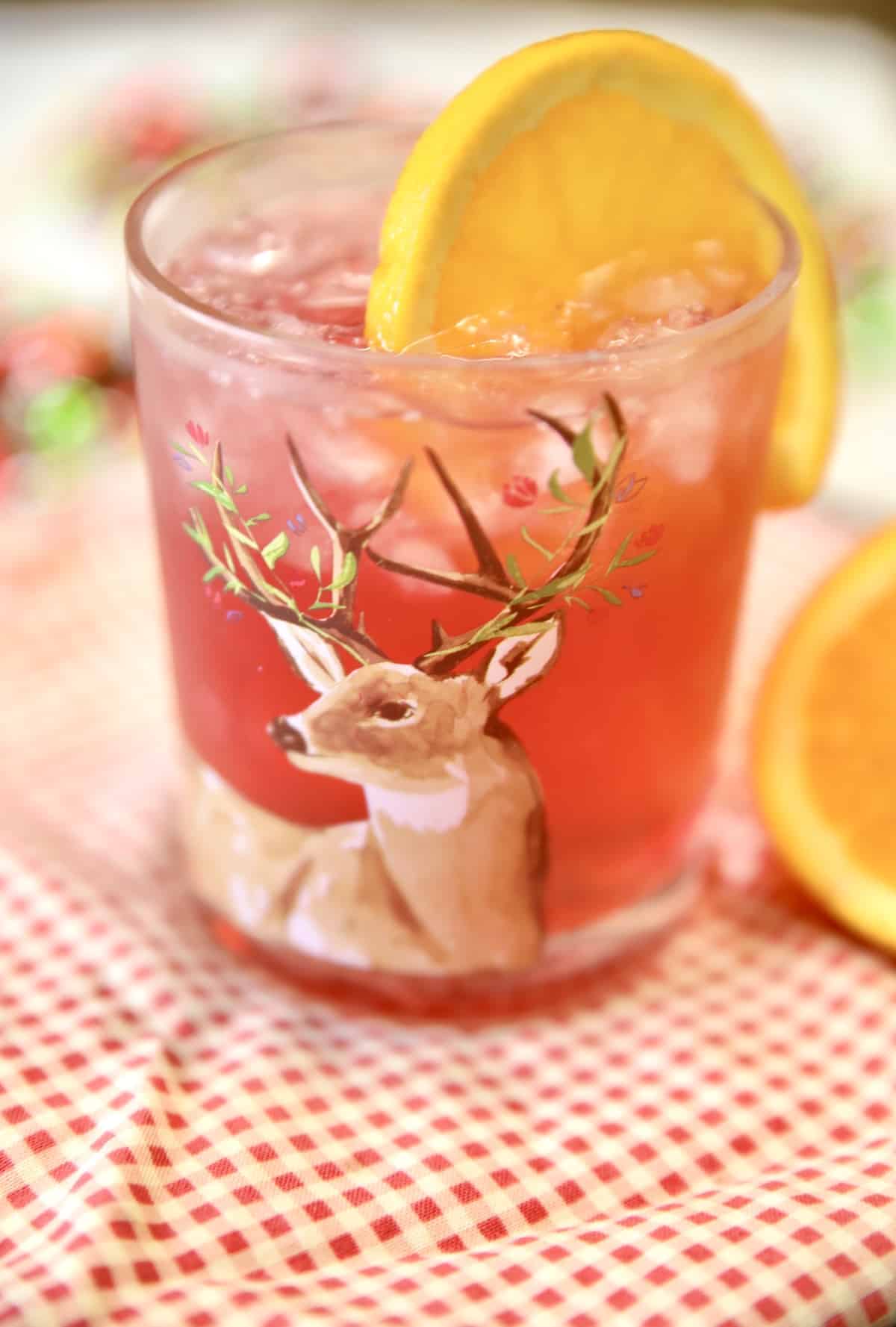 Glass of cranberry rum punch with orange slice.