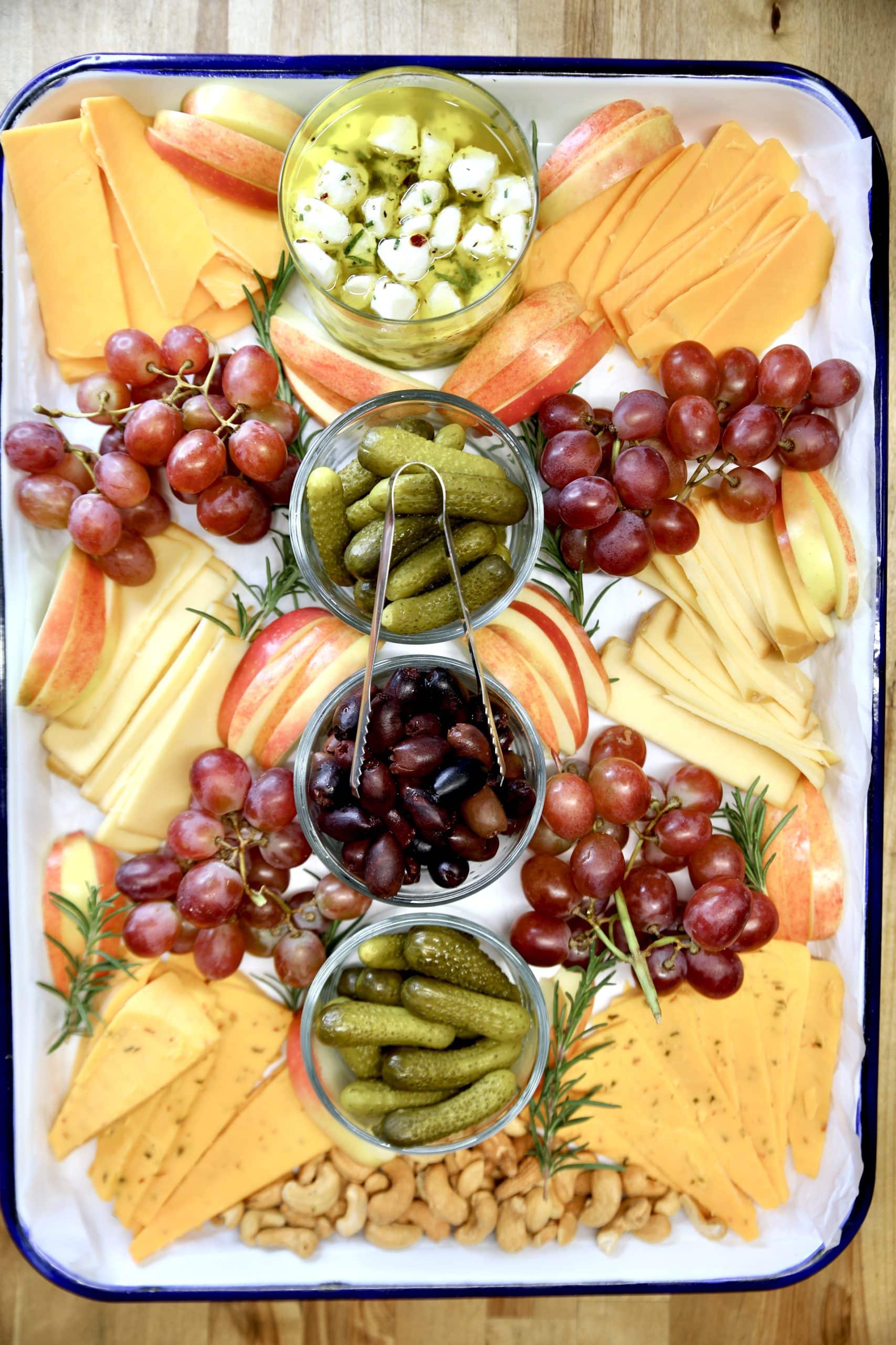 Cheese tray with marinated mozzarella, pickles, olives, fruit.