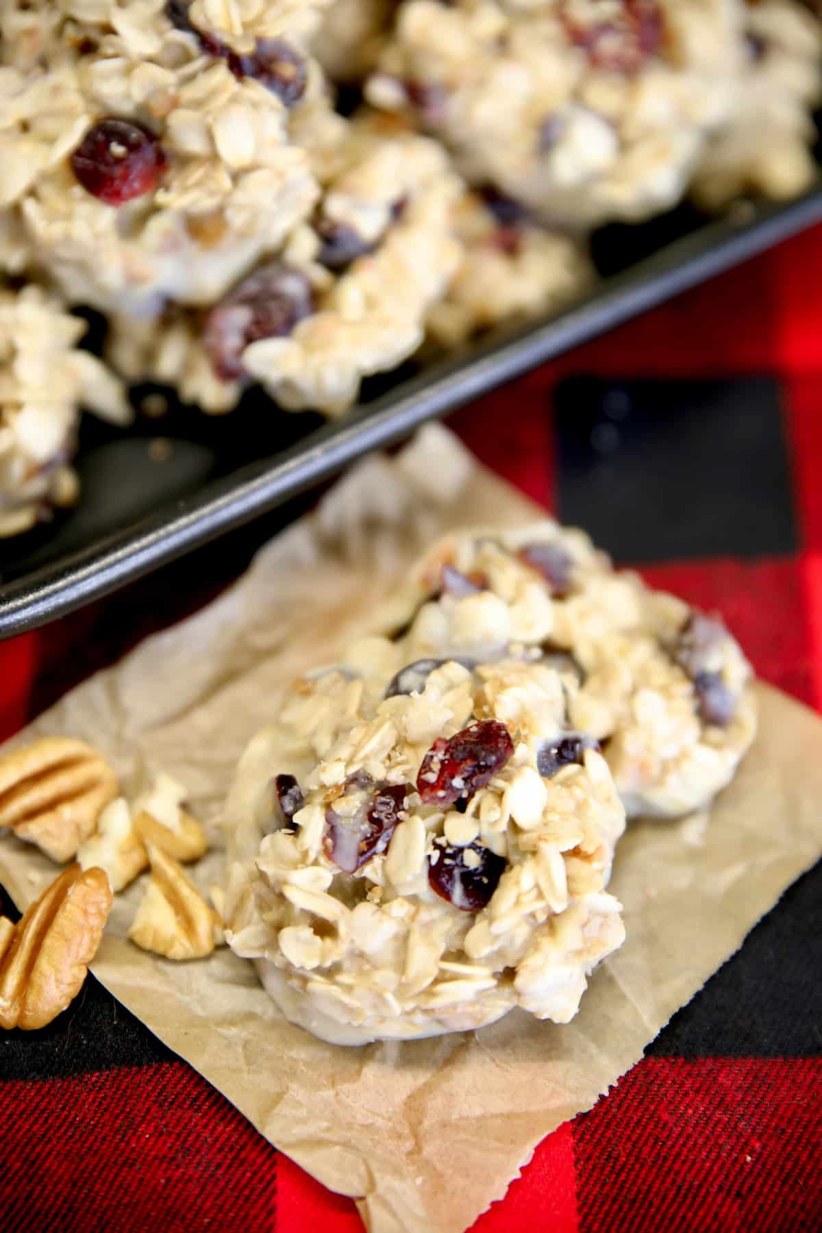 2 White chocolate cranberry cookies on a piece of parchment.