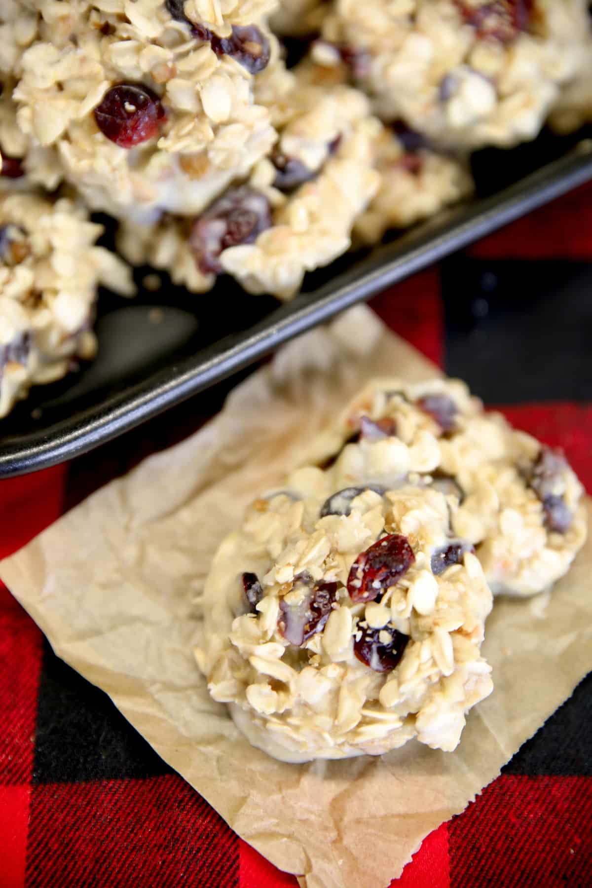 White chocolate cranberry cookies on a platter and on a piece of parchment.