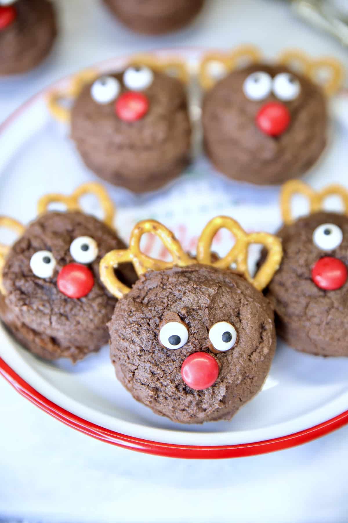 Reindeer cookies with pretzel antlers and candies on a plate.