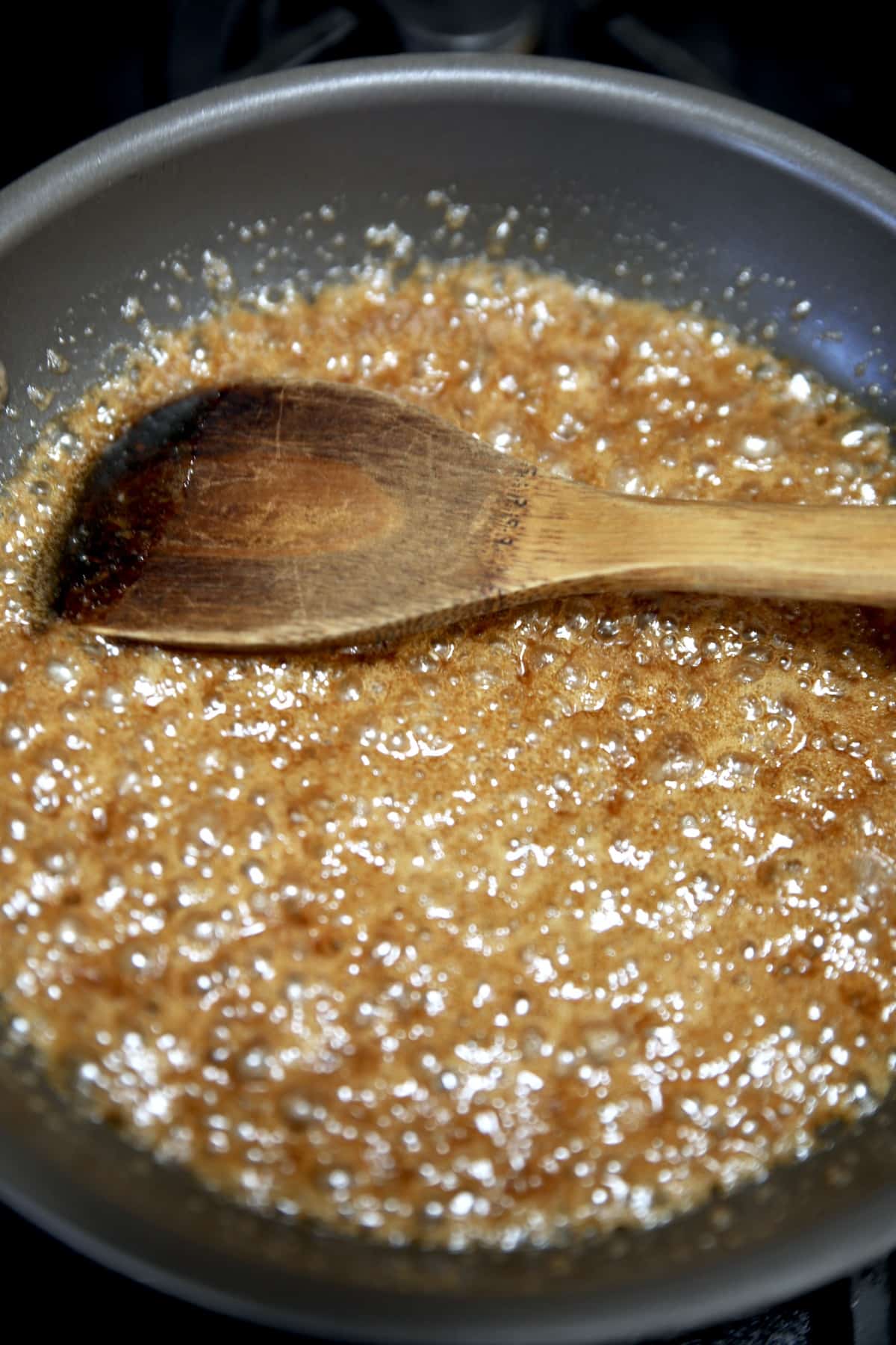 Buttered rum mixture for candied nuts with wooden spoon.