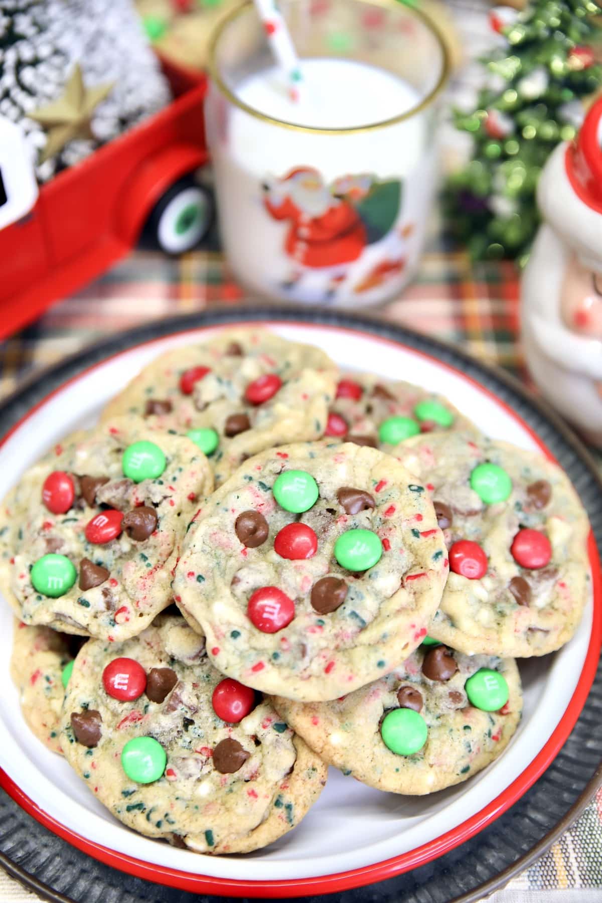 Platter of cookies with m&ms, Christmas decor, glass of milk.