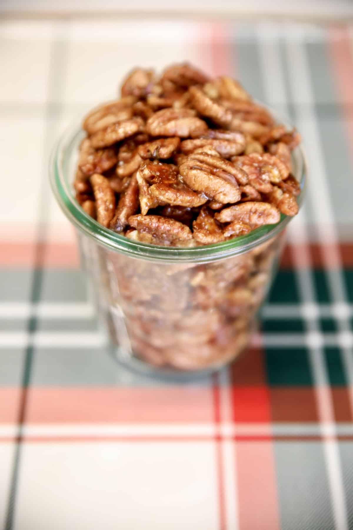 Jar of candied pecans on a plaid tray.
