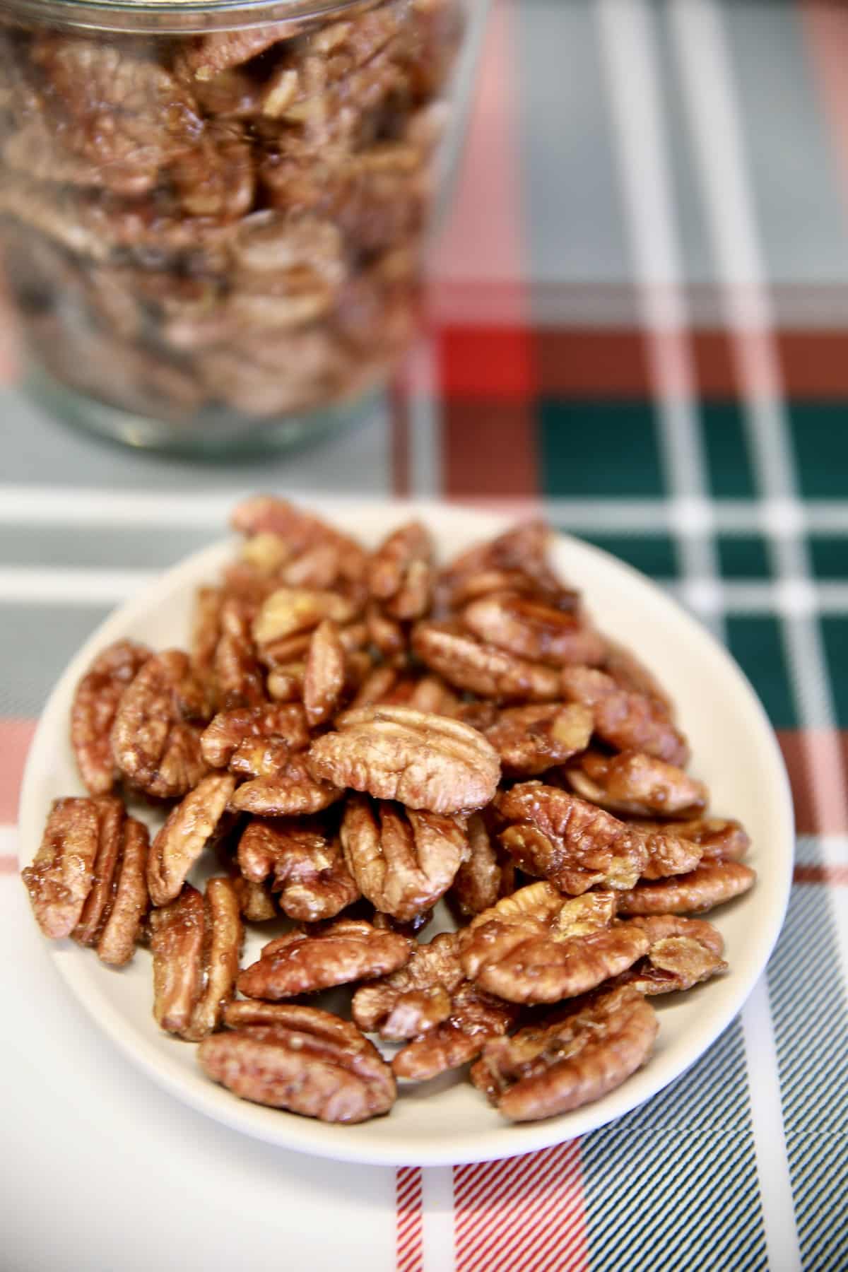 Bowl of candied pecans, jar in background.