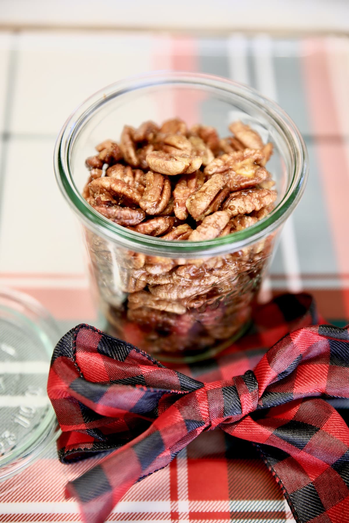 Jar of candied walnuts with holiday bow.