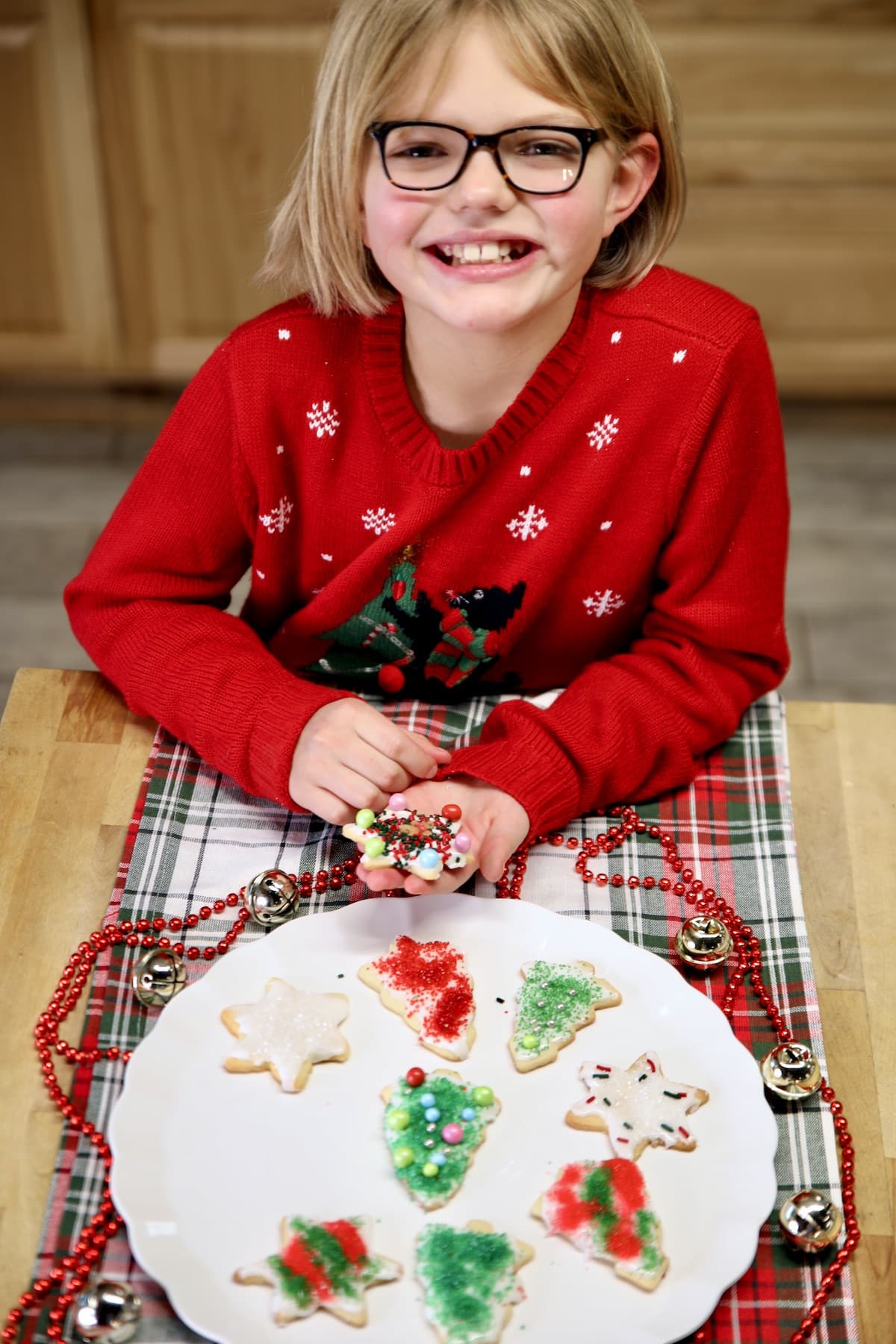 Girl with decorated sugar cookies on a tray.